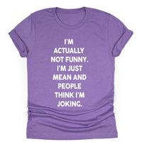 Purple unisex t-shirt with bold white text that reads: ‘I’m actually not funny. I’m just mean and people think I’m joking.’ Shirt laid flat with rolled sleeves.