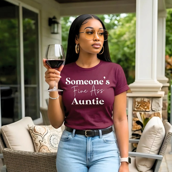 Woman holding a glass of wine and wearing a purple t-shirt with text in an outdoor setting.